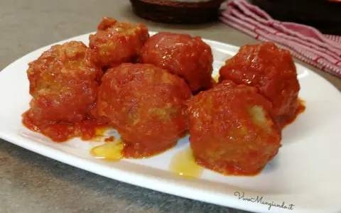 Polpette di pane al sugo, morbide e saporite, servite su un piatto bianco. Un classico della cucina italiana.