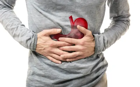 Uomo con mani sullo stomaco, dove un'immagine rossa evidenzia un possibile tumore allo stomaco.