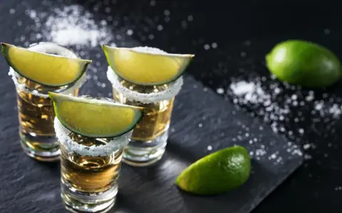 Szklanki z tequilą, ozdobione solą i ćwiartkami limonki. Idealne do picia z limonką, gdy zastanawiasz się, z czym pić tequilę.