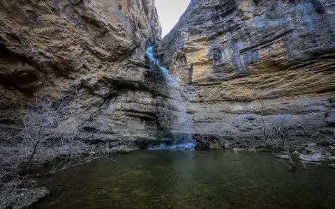 La cascada del Gollorio cae entre imponentes paredes rocosas, formando un estanque sereno.