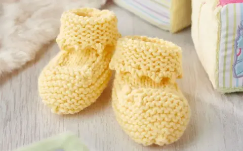 Patucos dos agujas de lana amarilla, perfectos para abrigar los pies de un bebé.