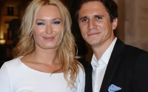 Uśmiechnięta para, być może rodzice Sambora Czarnoty, pozuje do zdjęcia. Kobieta ma blond włosy i białą sukienkę, mężczyzna czarny garnitur.