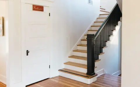 Escalier avec rampe noire et marches en bois clair. La question de peindre une cage d'escalier quelle couleur est ouverte.