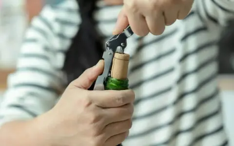 Ręce otwierają butelkę prosecco korkociągiem. Prosty sposób, jak otworzyć prosecco, by zacząć świętowanie.