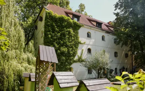 Oddział etnografii - spichlerz opacki, otoczony zielenią, z zabytkowymi ulami w ogrodzie.