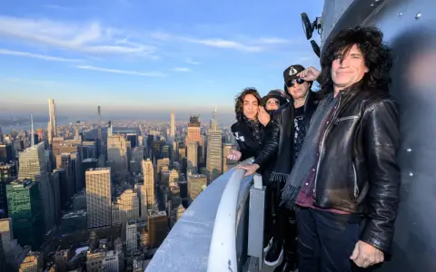 Les membres du groupe KISS posent sur un gratte-ciel new-yorkais, offrant une vue imprenable sur la ville.