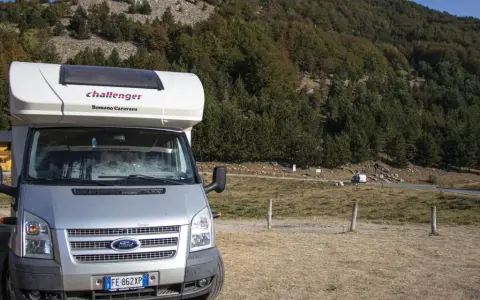 Camper parcheggiato in un'area panoramica della Calabria, con boschi e montagne sullo sfondo. Un'avventura in camper indimenticabile.