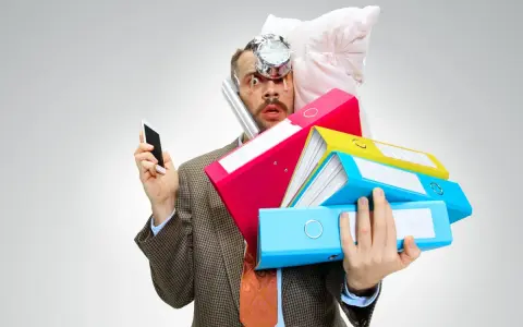 Uomo stressato con pile di cartelle, telefono e cuscino in testa. Lo stress aumenta il cortisolo, che fa ingrassare.