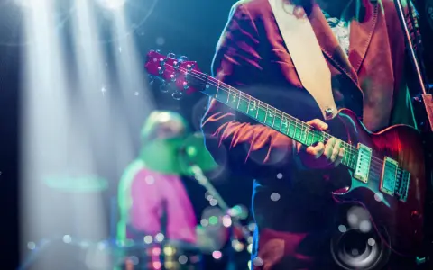 Koncertowe emocje! Gitarzysta gra na scenie, przypominając najlepsze zagraniczne zespoły lat 90. W tle perkusista.