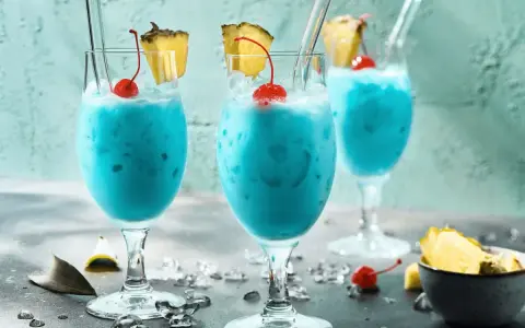 Erfrischende blaue Swimmingpool-Cocktails mit Ananas und Kirschen, bereit für den Sommer.