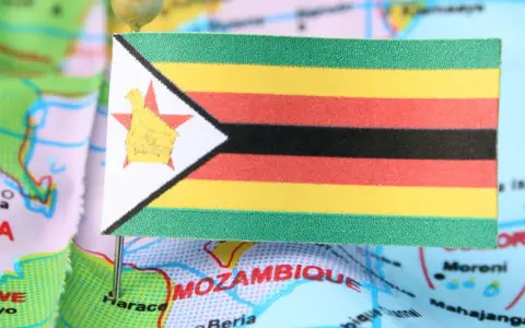 Flaga Zimbabwe na mapie, symbolizująca trudności gospodarcze i inflację.