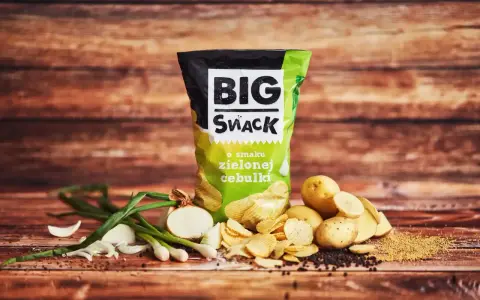 Reklamowa fotografia chipsów Big Snack o smaku zielonej cebulki, z ziemniakami i cebulką.