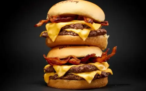Dos hamburguesas caseras apiladas, con doble carne, queso fundido y crujiente tocino.