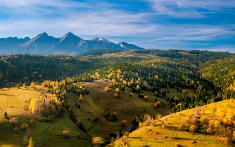 Jesienne Tatry Słowackie zachwycają kolorami. Widok na łagodne wzgórza i lasy, idealne na szlaki dla średnio zaawansowanych.