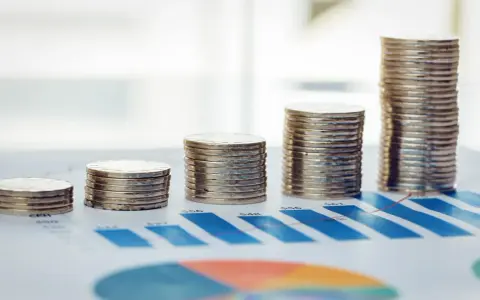 Rosnące stosy monet na wykresie symbolizują walkę z deficytem budżetowym i dążenie do stabilności finansowej.
