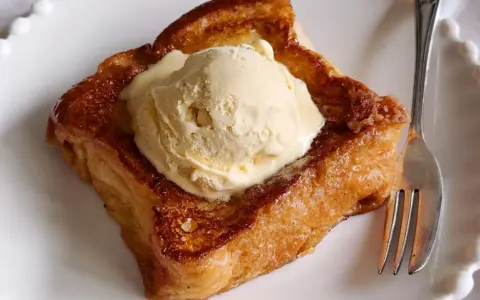 Torrijas con pan brioche, doradas y crujientes, coronadas con una generosa bola de helado de vainilla. Un postre irresistible.