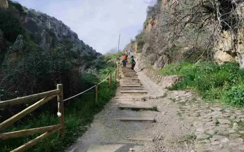 Senderos de montaña con escalones de piedra y madera. Personas caminan por las rutas Patones de Arriba, rodeadas de vegetación y acantilados.