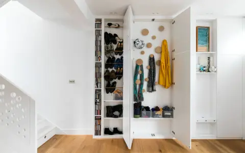 Moderne Garderobe Ideen: Offene Fächer mit Schuhen, Jacken und Schals. Ein Fahrradhelm hängt an der Wand.