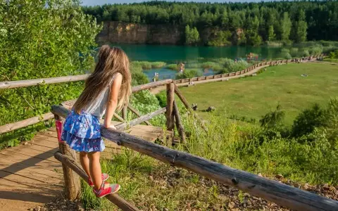 Dziewczynka na drewnianej kładce podziwia Park Gródek Jaworzno. Warto sprawdzić cenę wstępu, by cieszyć się tym widokiem!