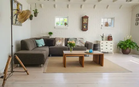 Un salon moderne avec poutre apparente, canapé confortable, table basse en bois et murs en briques blanches.