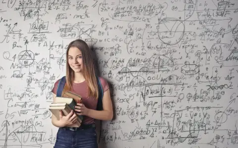Uśmiechnięta studentka z książkami przed ścianą pełną równań matematycznych. Zastanawia się, co po studiach matematycznych.
