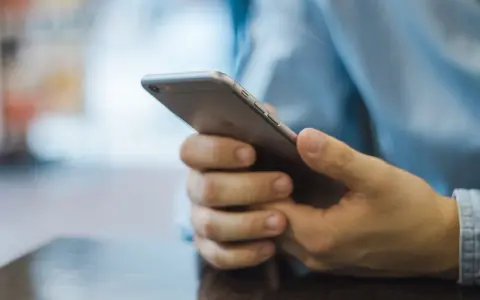 Dłonie trzymające smartfon, szukające inspiracji, jak zacząć rozmowę na Badoo.