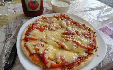 Pyszna pizza z patelni z serem, pomidorami i kukurydzą, obok ketchup i sos.
