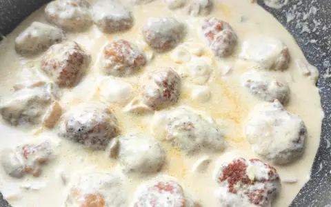 Pyszne klopsiki w sosie śmietanowym, gotujące się na patelni. Aromatyczne danie, które zachwyci każdego.