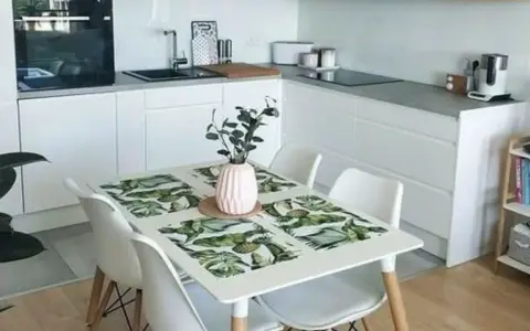 Cocinas pequeñas con mesa para comer, un espacio funcional y moderno con encimeras blancas, electrodomésticos integrados y una mesa con mantel tropical.
