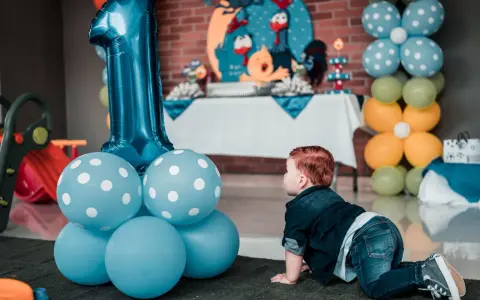 Niño gateando junto a globos azules y un gran número 1. Ideas para como preparar una fiesta infantil barata y muy original.