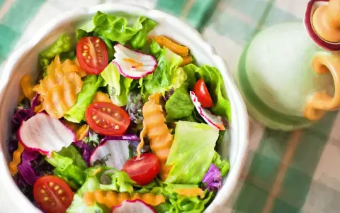Unas frescas ensaladas de verano con lechuga, tomate, rábano y zanahoria rallada, listas para disfrutar.