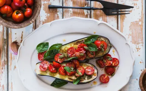 Melanzane ripiene vegetariane con pomodorini, basilico e semi di zucca, un piatto colorato e saporito.