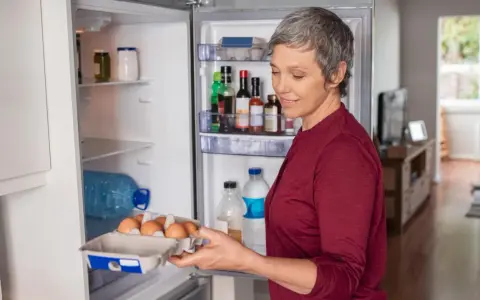 Frau holt Eier aus dem Kühlschrank. Nach einer Darmspiegelung ist leichte Kost wie Eier oft das erste Essen.