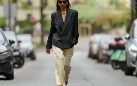 Mujer con blazer negro y pantalones de lino a rayas. Aprende como lavar pantalones de lino para mantenerlos impecables.