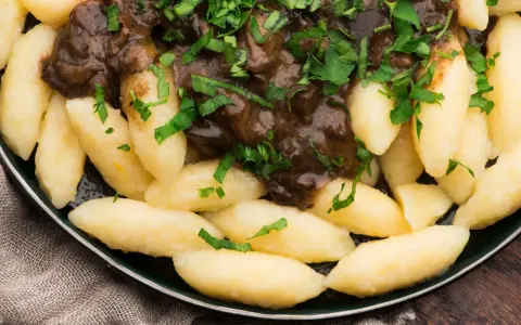 Kopytka z gulaszem, jak u babci! Pyszne ciasto na kopytka przepis babci, polane aromatycznym sosem i posypane natką pietruszki.