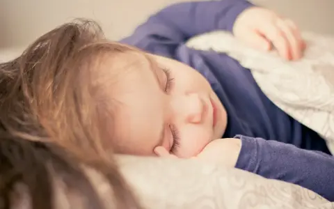 Dziecko śpi spokojnie, choć czasem **moczenie nocne na tle nerwowym** może zakłócać sen.