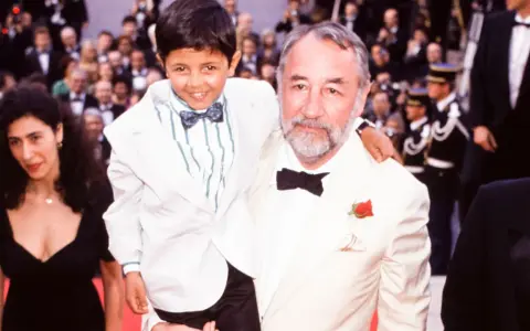 Un bambino sorridente, protagonista di "Nuovo Cinema Paradiso", abbracciato da un uomo con una rosa all'occhiello.