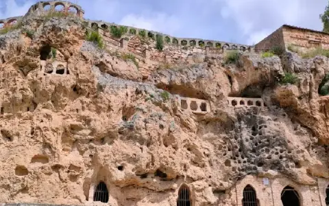 Antigua ciudad excavada en roca, con arcos y ventanas en las cuevas. Un lugar histórico que parece una cascada de piedra.