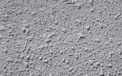 Textura gris de pared con relieve irregular, típica del **el gotelé**, que crea un efecto rugoso y con pequeñas protuberancias.