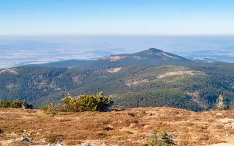 Widok z trasy na Śnieżnik. Góry pokryte lasem, na horyzoncie widać doliny i kolejne pasma górskie.