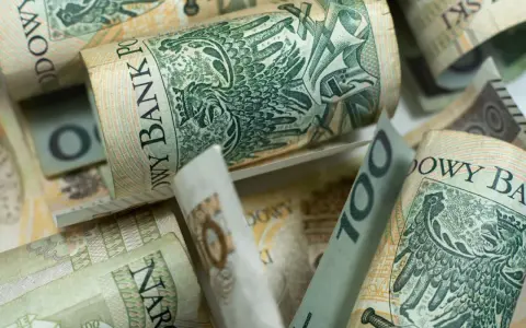Zwijane banknoty 100 zł, symbolizujące wsparcie finansowe, jak zasiłek rodzicielski, dla młodych rodzin.