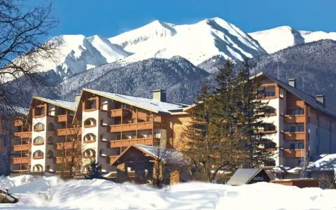 Bułgaria polecane hotele w górach. Zimowy krajobraz z ośnieżonymi szczytami i hotelami z drewnianymi balkonami.