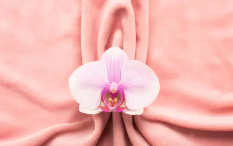 Delikatna orchidea na różowym tle, symbolizująca piękno i kobiecość, nawiązuje do tematu wycinania warg sromowych.
