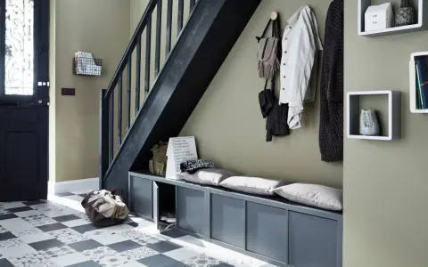 Escalier moderne avec une couleur tendance, banc de rangement gris, porte d'entrée noire et sol à motifs.