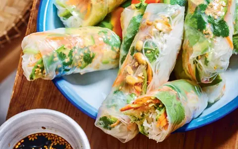 Rouleaux de printemps frais et colorés, parfaits pour une recette facile. On y voit des vermicelles de riz, des légumes croquants et des cacahuètes.