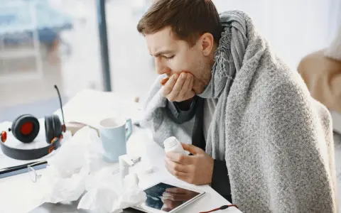 Uomo malato, avvolto in una coperta, prende una pillola. Spera che l'aspergillus si guarisca presto.