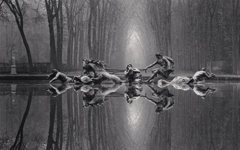 Rzeźby w stawie, koń i ludzie, odbijają się w wodzie. Styl Michael Kenna.