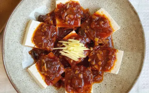 Tofu comida servida en un plato con salsa picante y jengibre rallado.