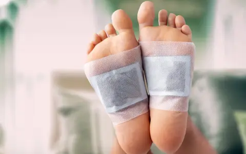 Close-up of feet with detox patches applied to the soles, demonstrating how to do a foot detox at home.