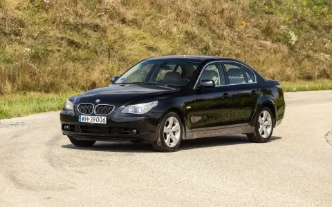 Czarne BMW 535d na tle zielonego wzgórza.